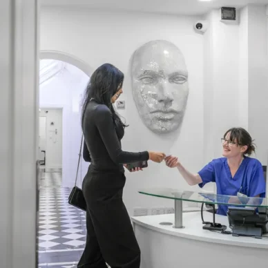 patient checking in at clinic reception with staff in blue scrubs
