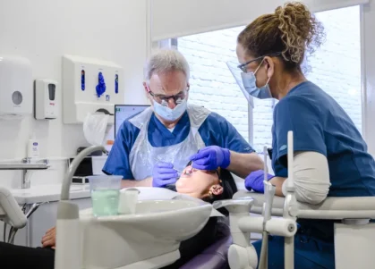 orthodontist and dental assistant treating a patient in a dental chair